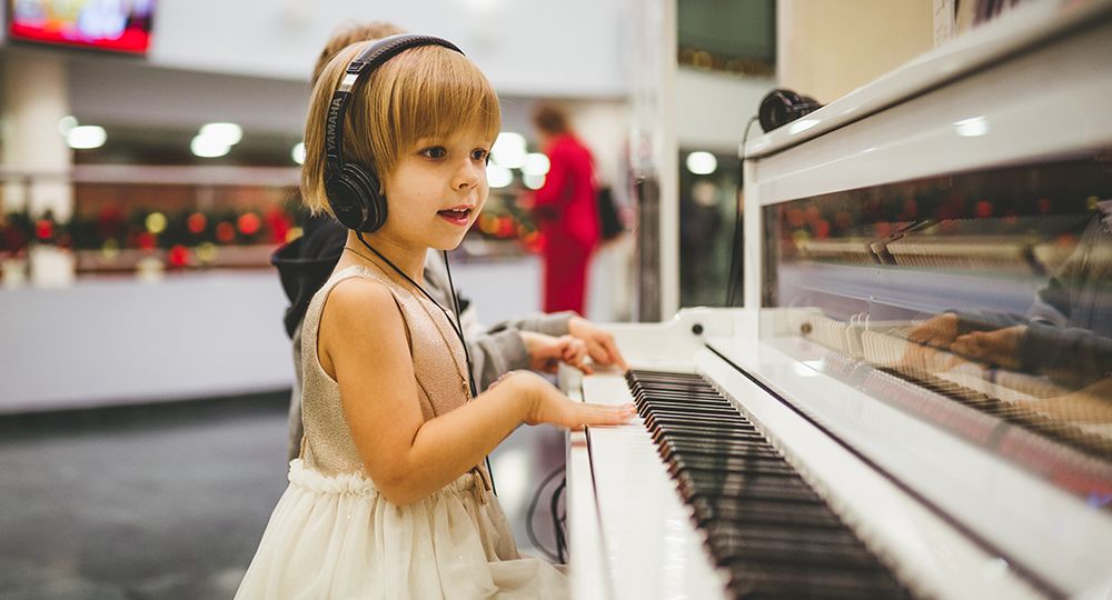 niña aprendiendo a tocar el piano para desarrollar su inteligencia musical